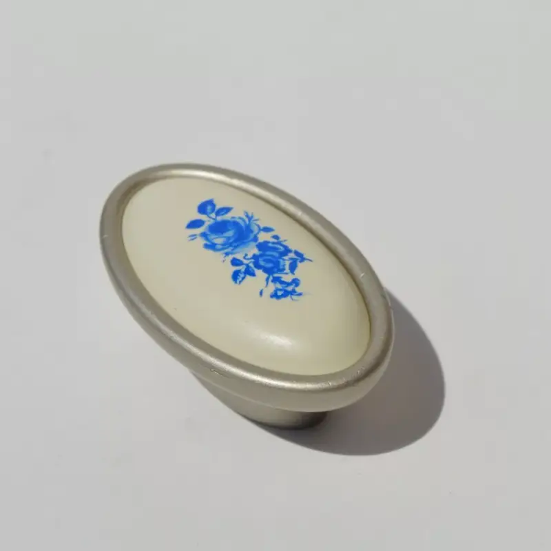 Fém-műanyag bútorfogantyú, pezsgő színű, kék virág mintával, 16 mm furattávval Olcsó