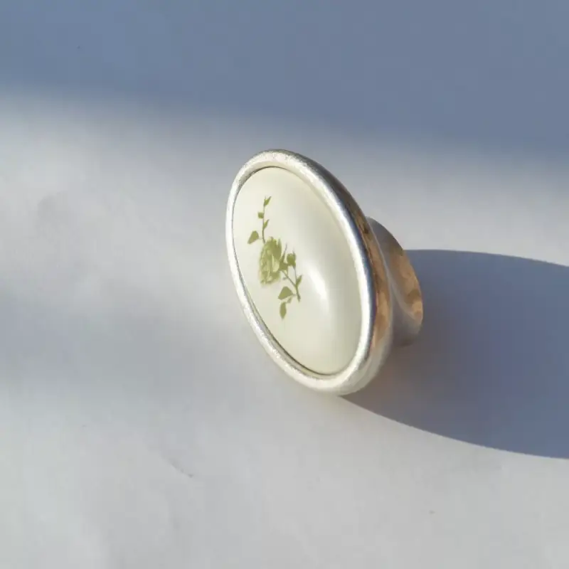 Akció Fém-műanyag bútorfogantyú, újezüst színű, zöld virág mintával, 16 mm furattávval